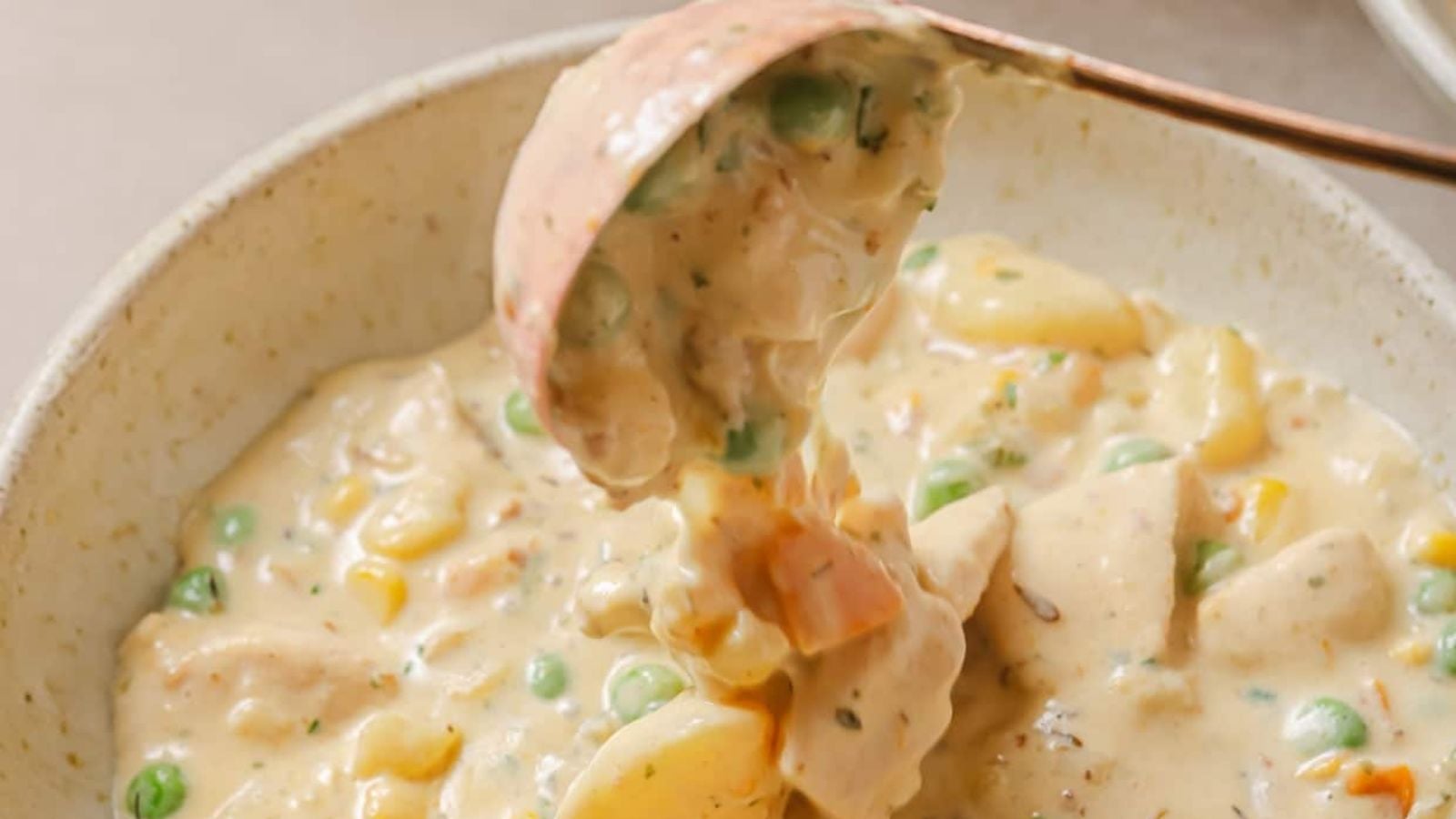 Chicken pot pie soup in a white bowl with a spoon.