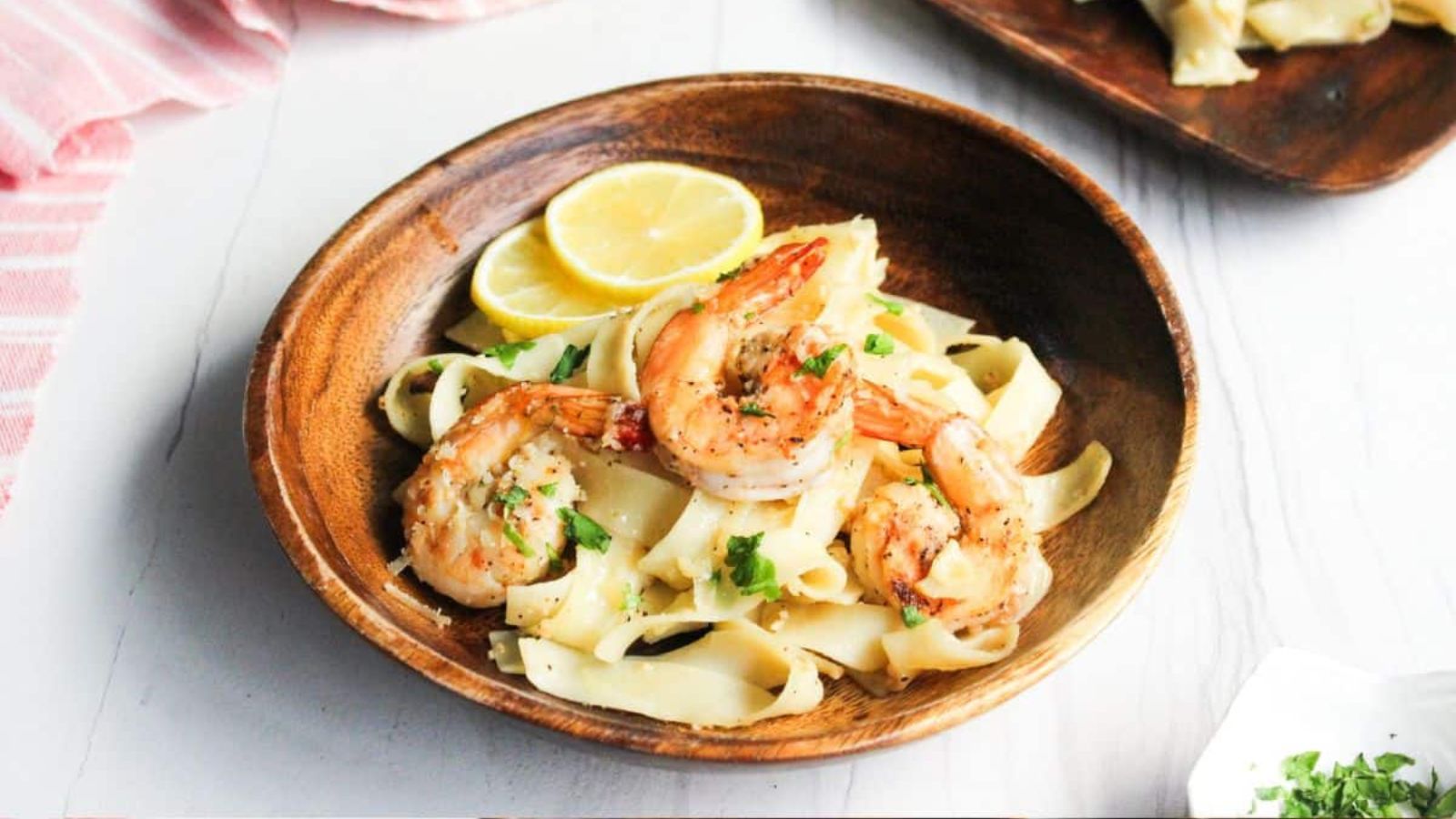 A bowl of shrimp pasta with lemon and parsley.