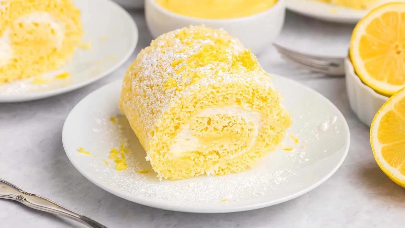 Lemon cake roll dusted with powdered sugar and filled with creamy lemon filling.