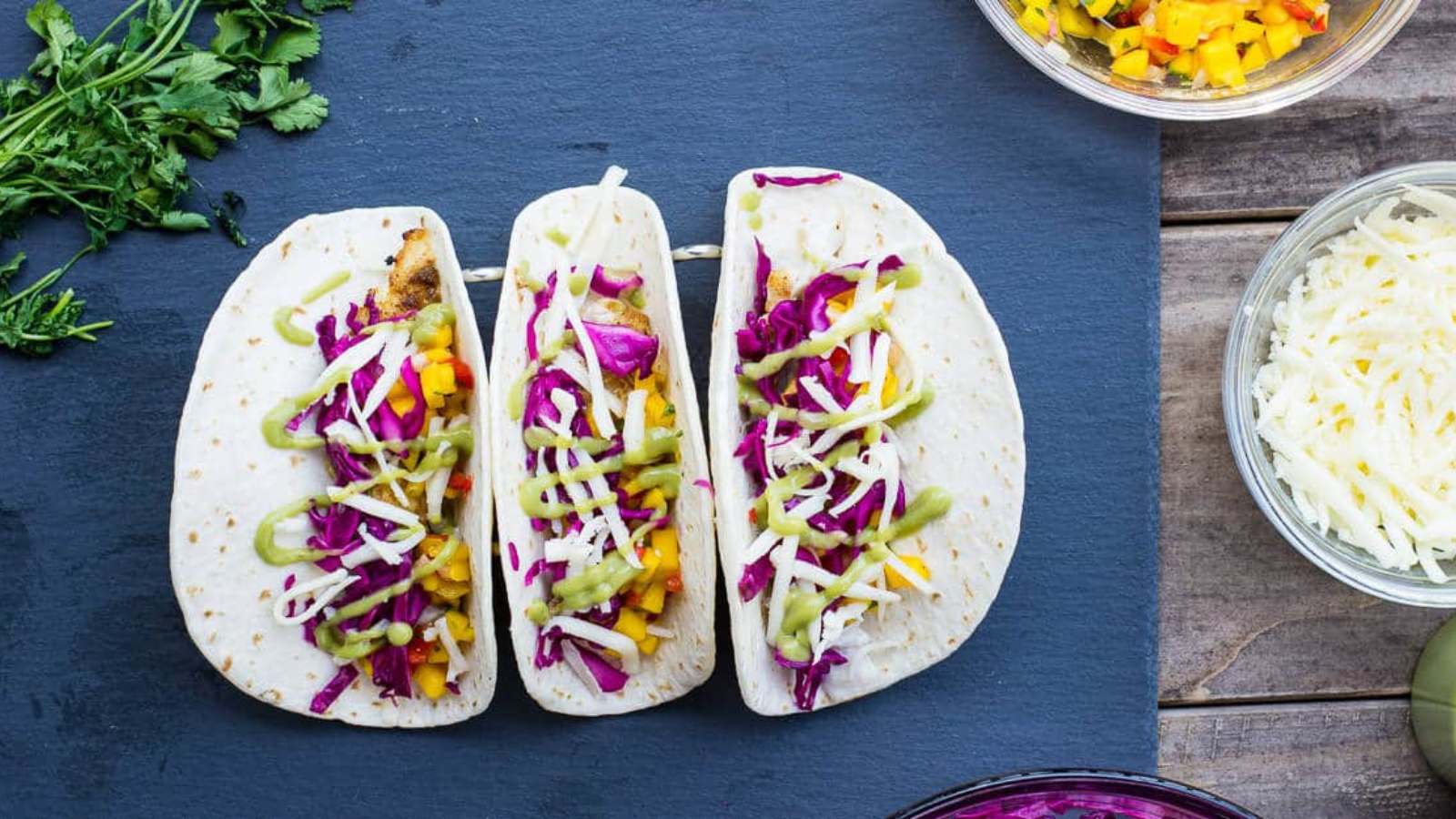 Grilled rockfish tacos assembled on a blue board.