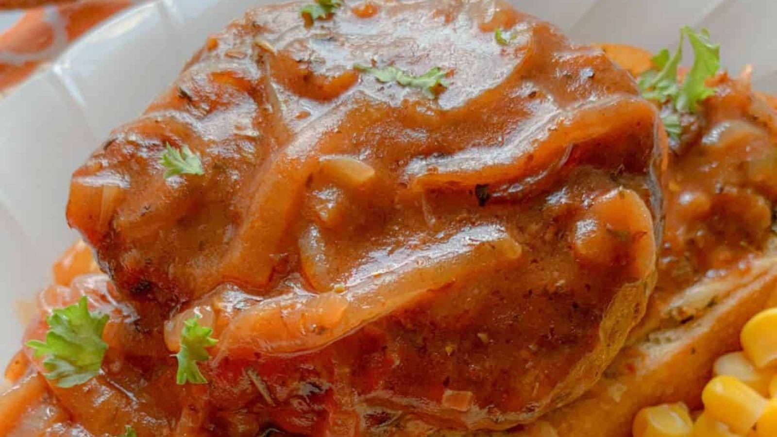 Salisbury Steak with brown gravy on cheese toast with corn and mashed potatoes on a dinner plate.