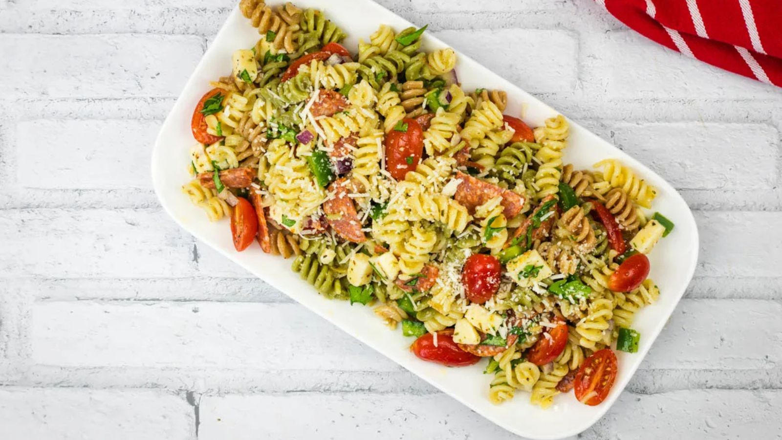 A platter of pizza pasta salad served on a white rectangular dish.