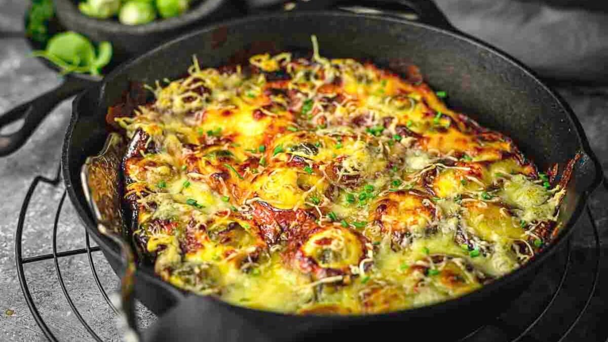 A casserole with brussel sprouts topped with cheese.