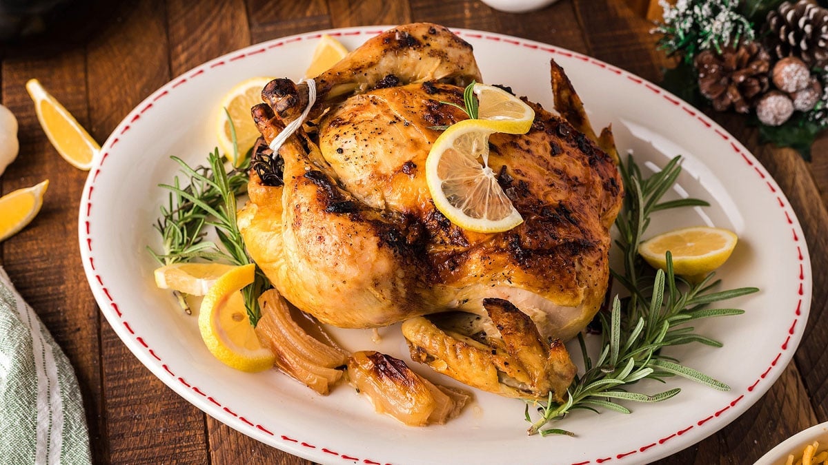 Whole holiday roasted chicken with golden skin served on a platter.