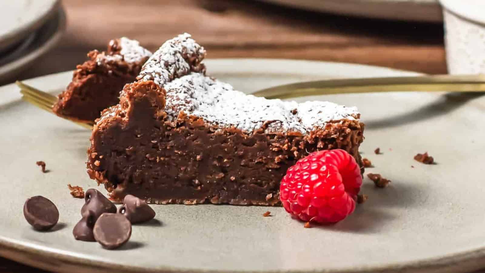 A chocolate cake dusted with powdered sugar, with raspberries and a cup of coffee on a wooden table.