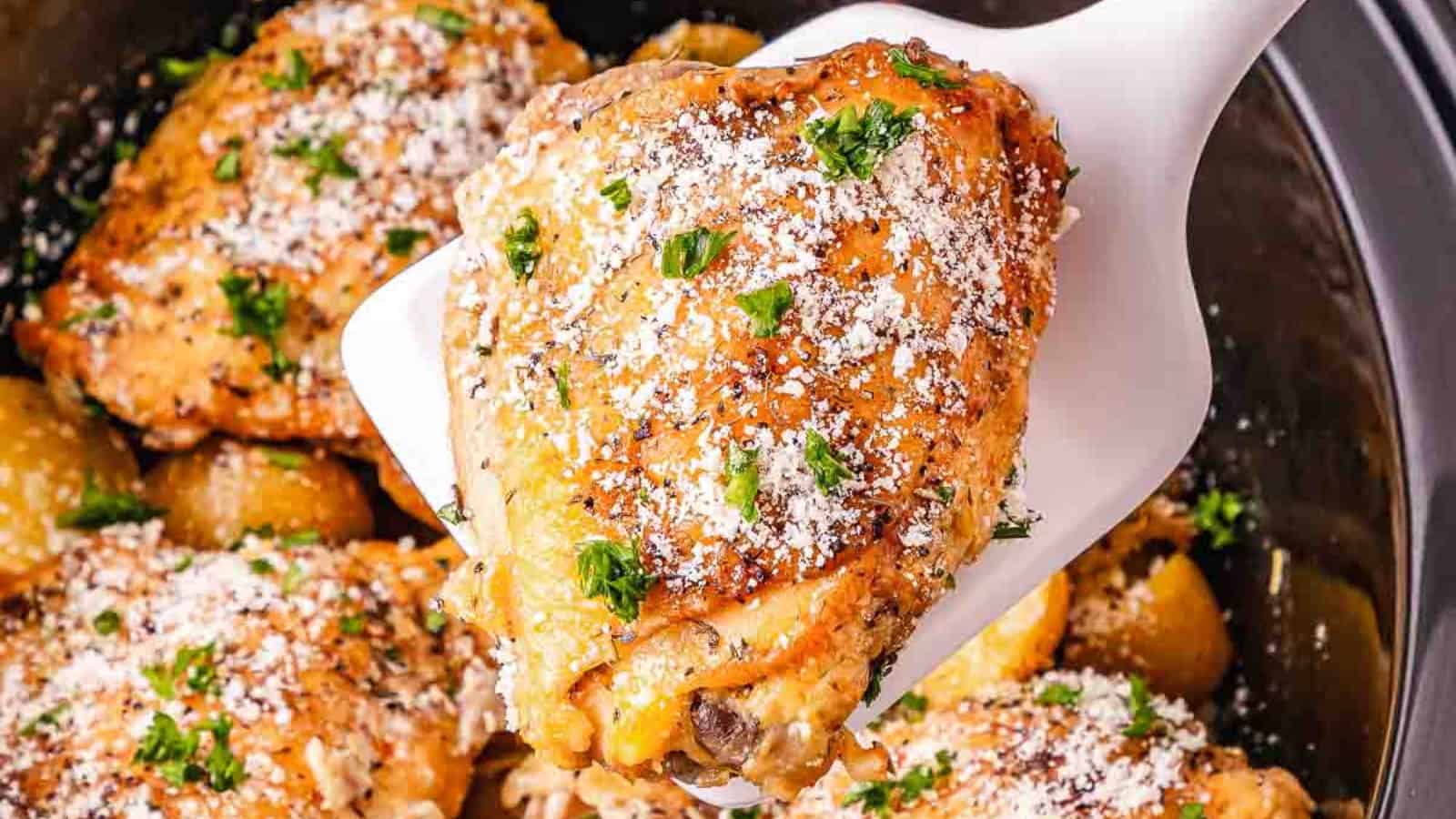 A plate of roasted chicken and baby potatoes, garnished with herbs and grated cheese, on a red-striped napkin.
