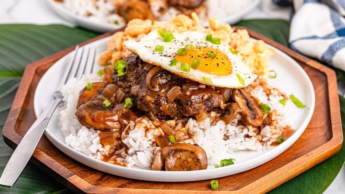 Rice layers under a hamburger patty, gravy, and a fried egg to build a complete loco moco plate.