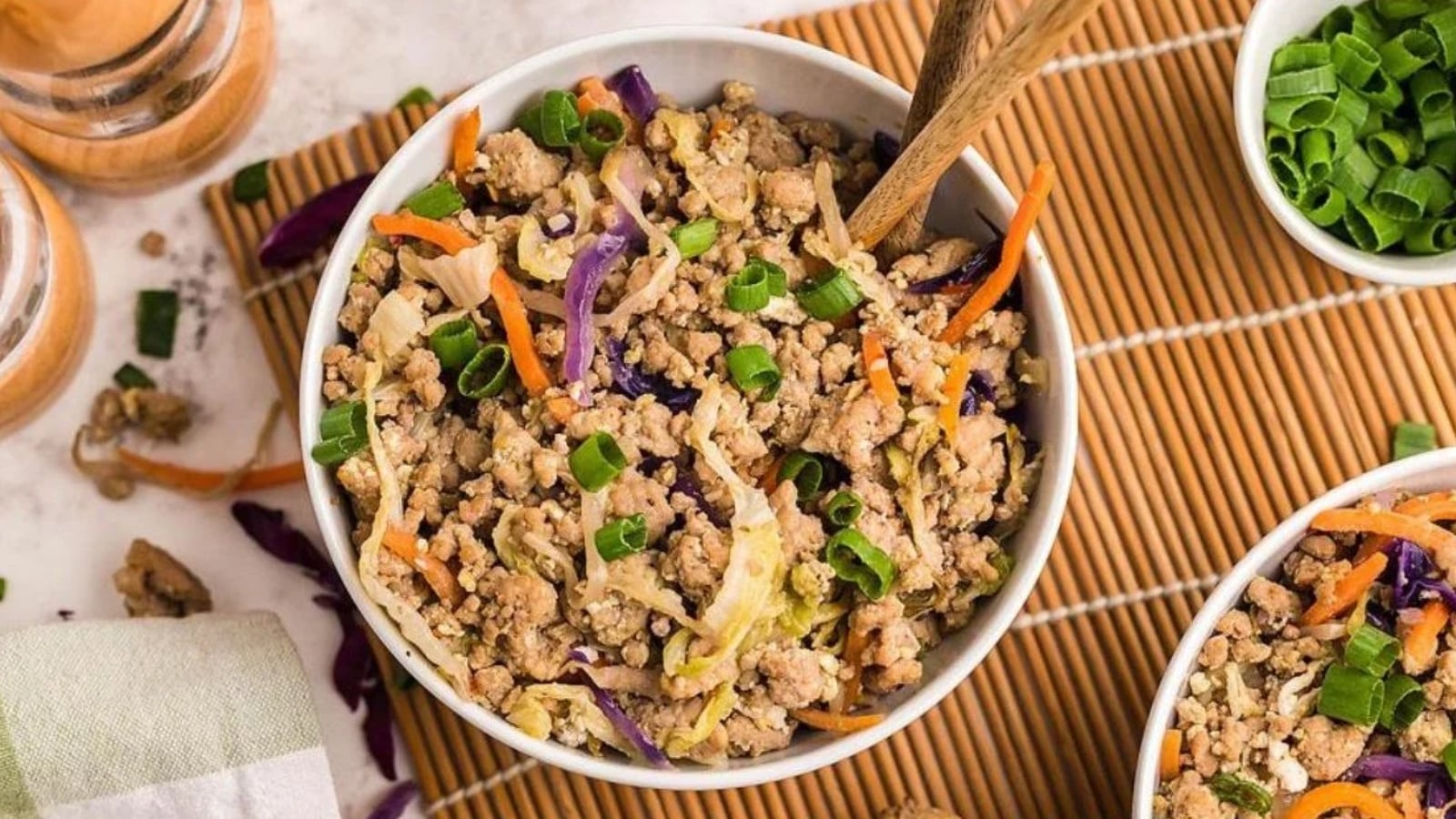 Ground pork egg roll in a bowl with cabbage, carrots, and green onions served with chopsticks.