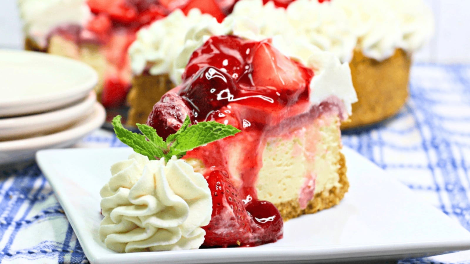Slice of strawberry cheesecake with whipped cream and strawberry topping on a plate.