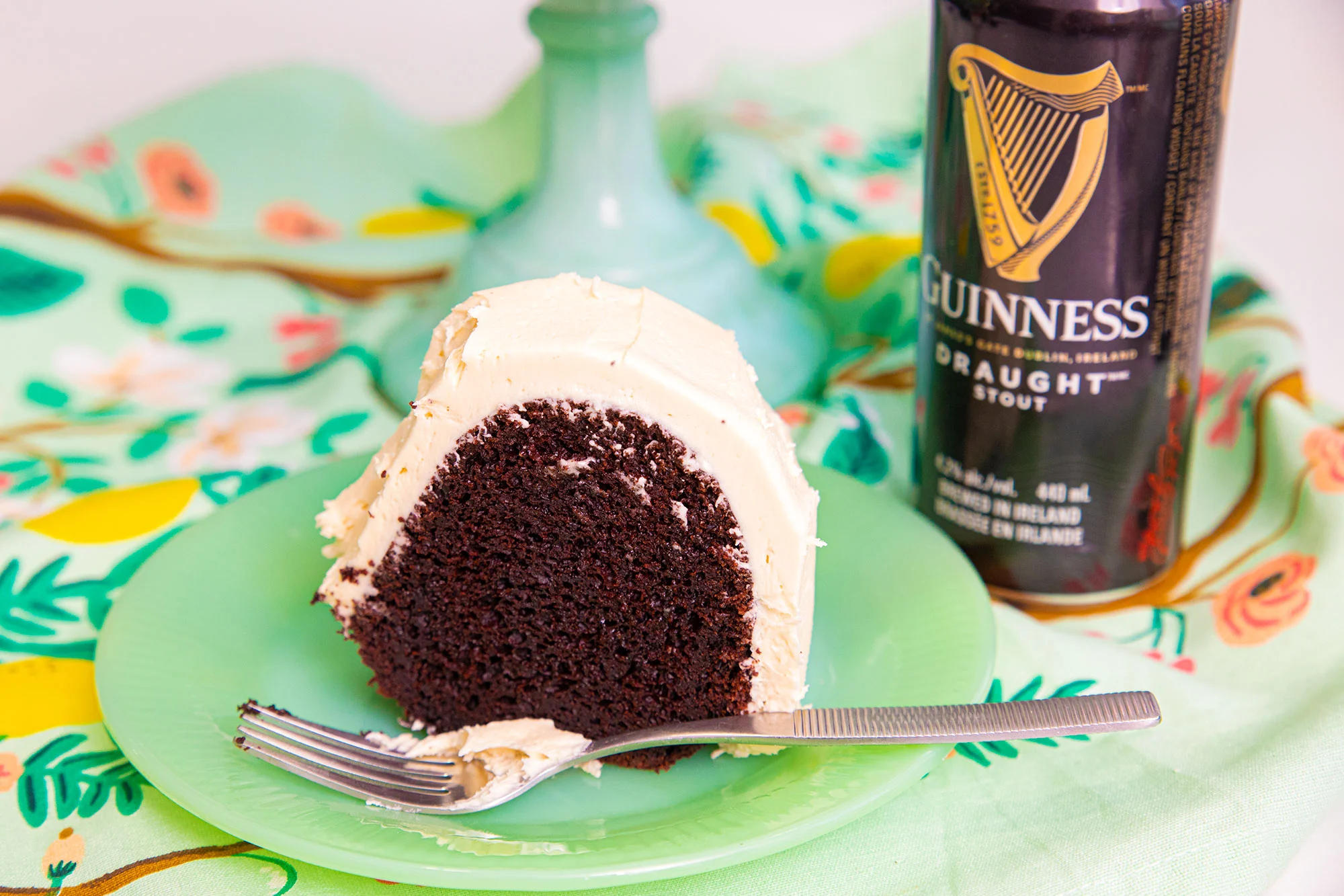 Slice of Guinness chocolate cake with frosting on a plate.