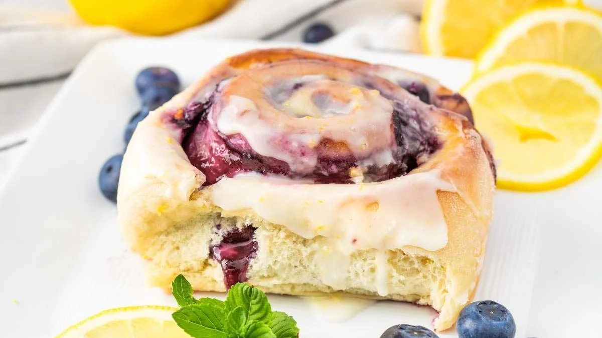 Lemon roll with blueberries on a plate.