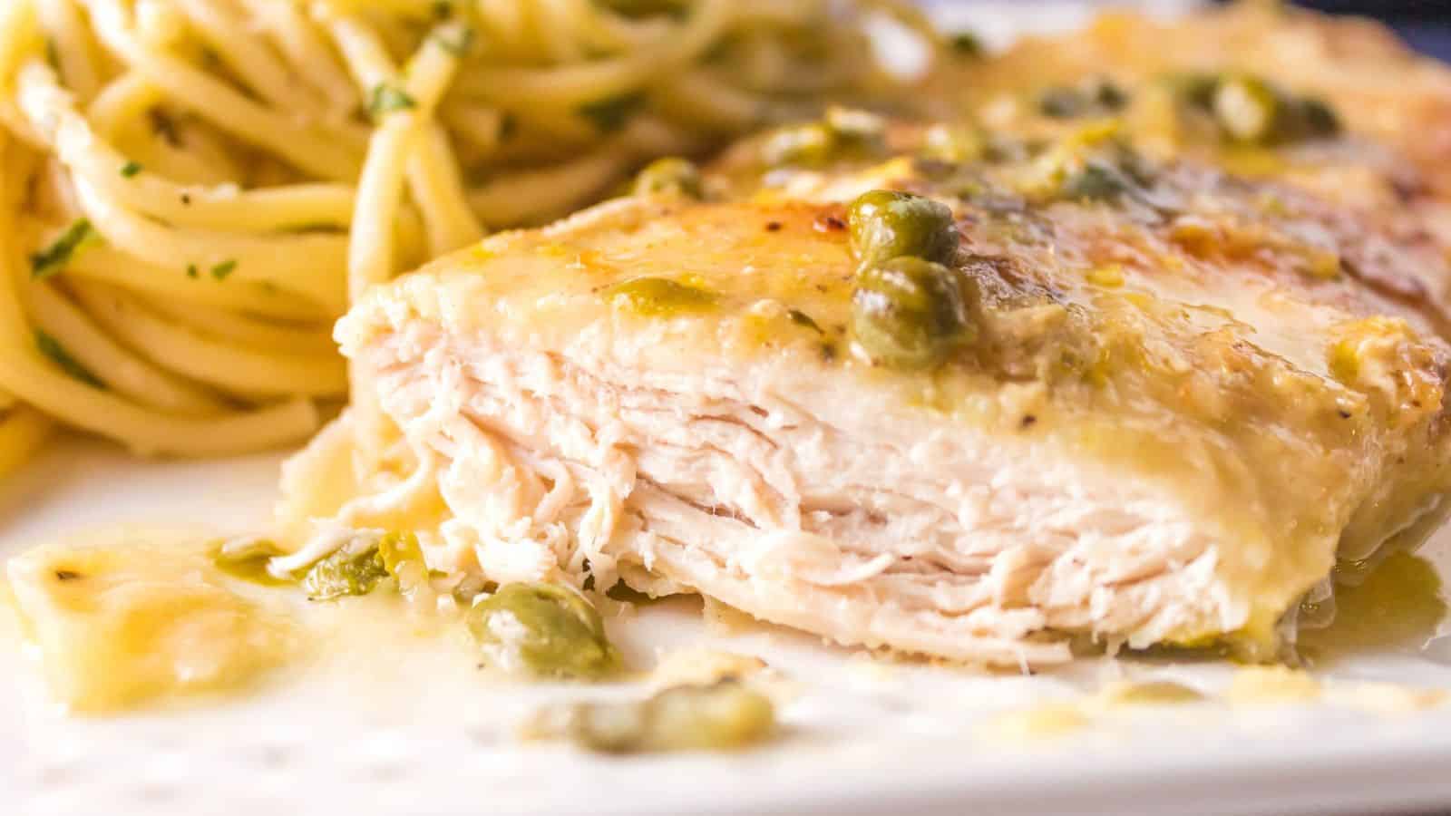 Chicken breast cut with pasta in the background.