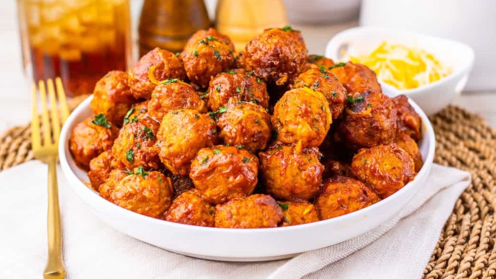 A bowl filled with saucy meatballs garnished with chopped parsley.