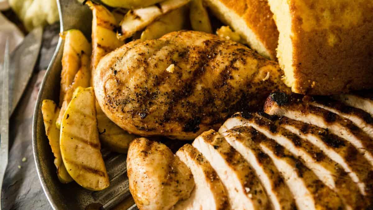 BBQ chicken breasts topped with grilled Granny Smith apple slices showing char marks and caramelized edges.