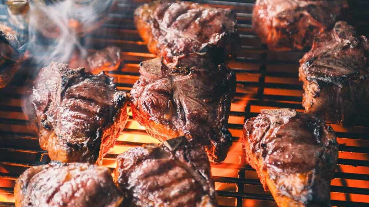 Grilled lamb loin chops with charred edges and fresh herbs scattered across the serving platter.