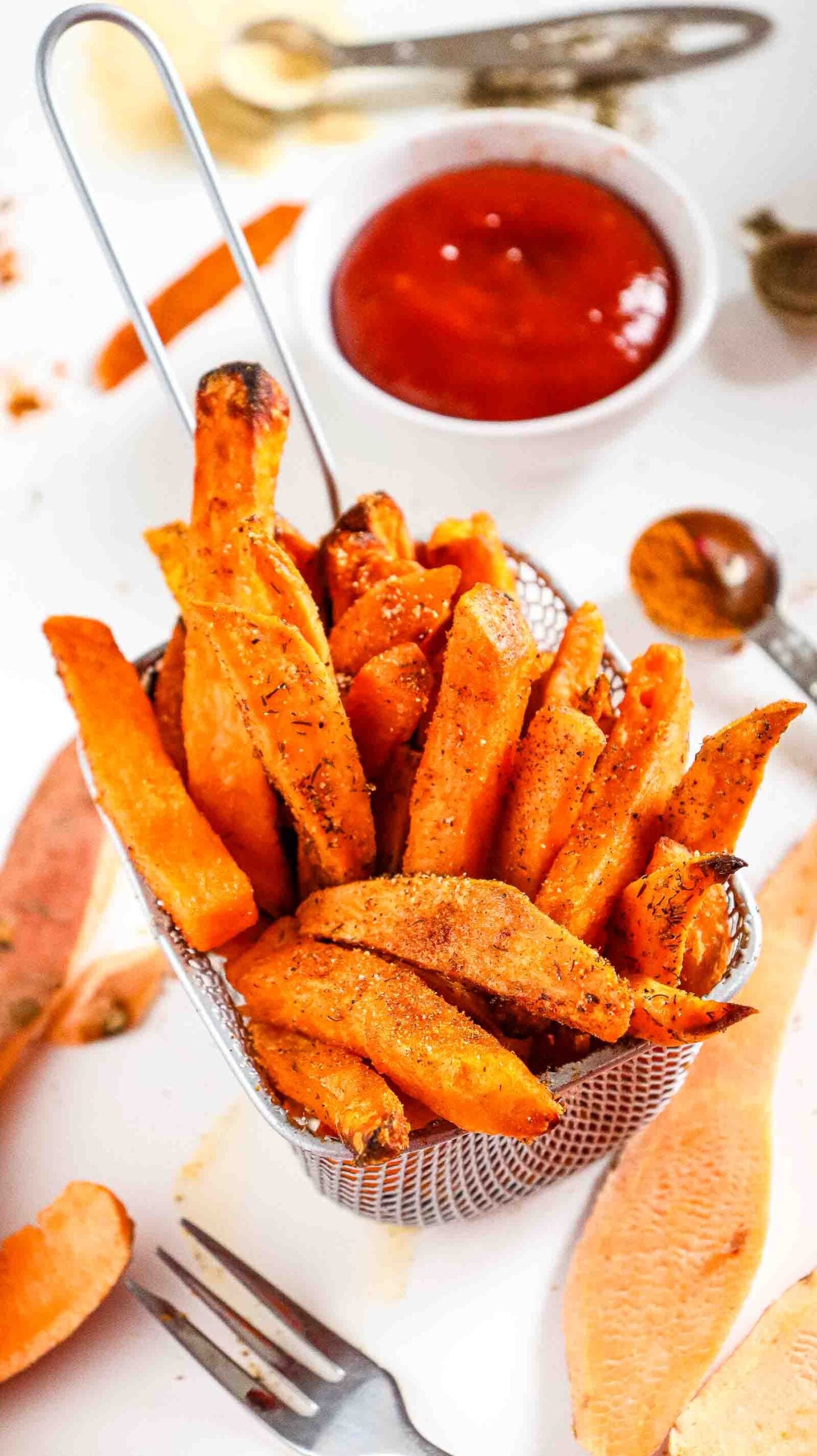 Overhead vertical shot of crispy air fryer sweet potato fries in a basket with dipping sauce.